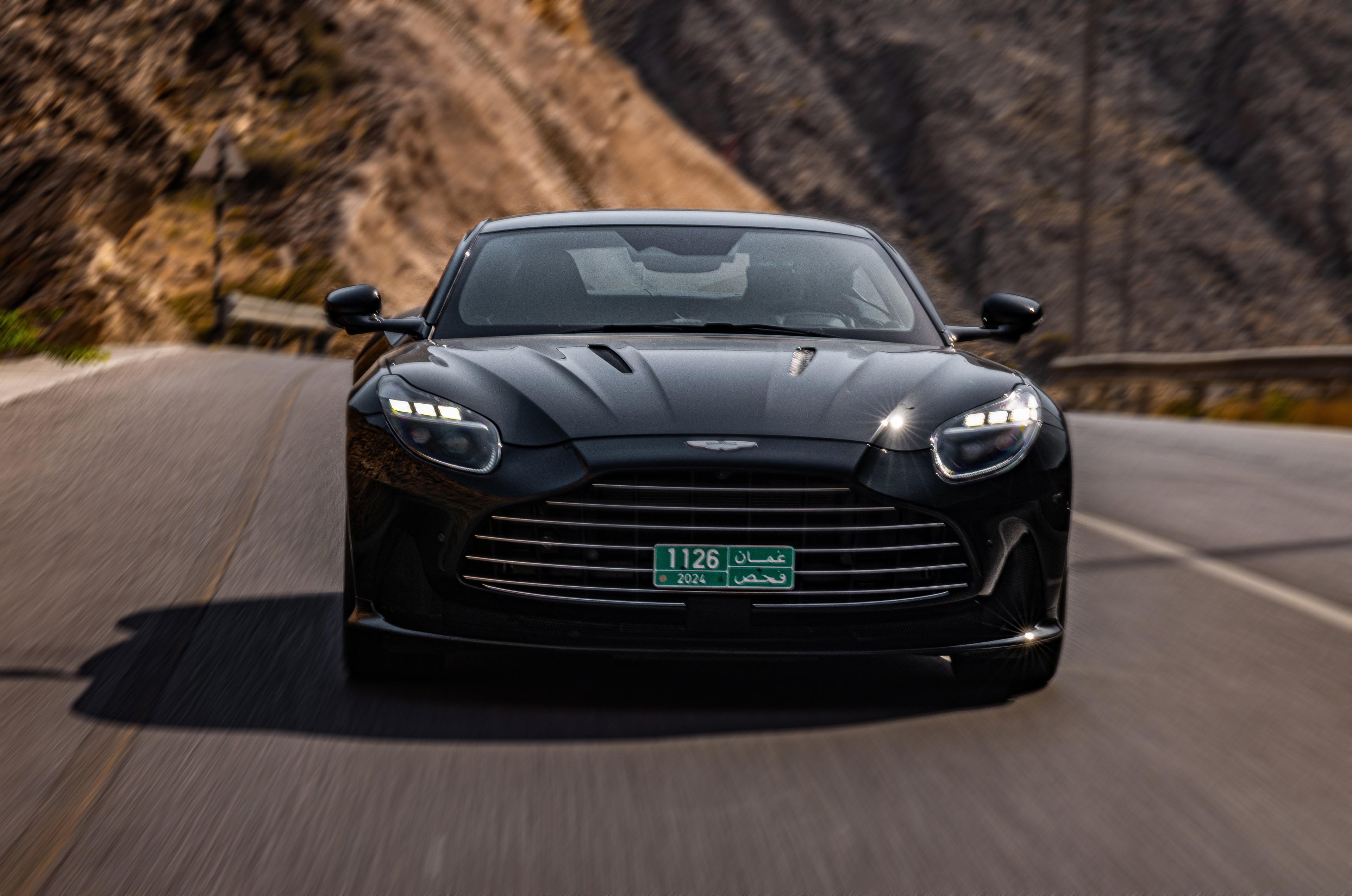 Black Aston Martin front rolling on a mountain road