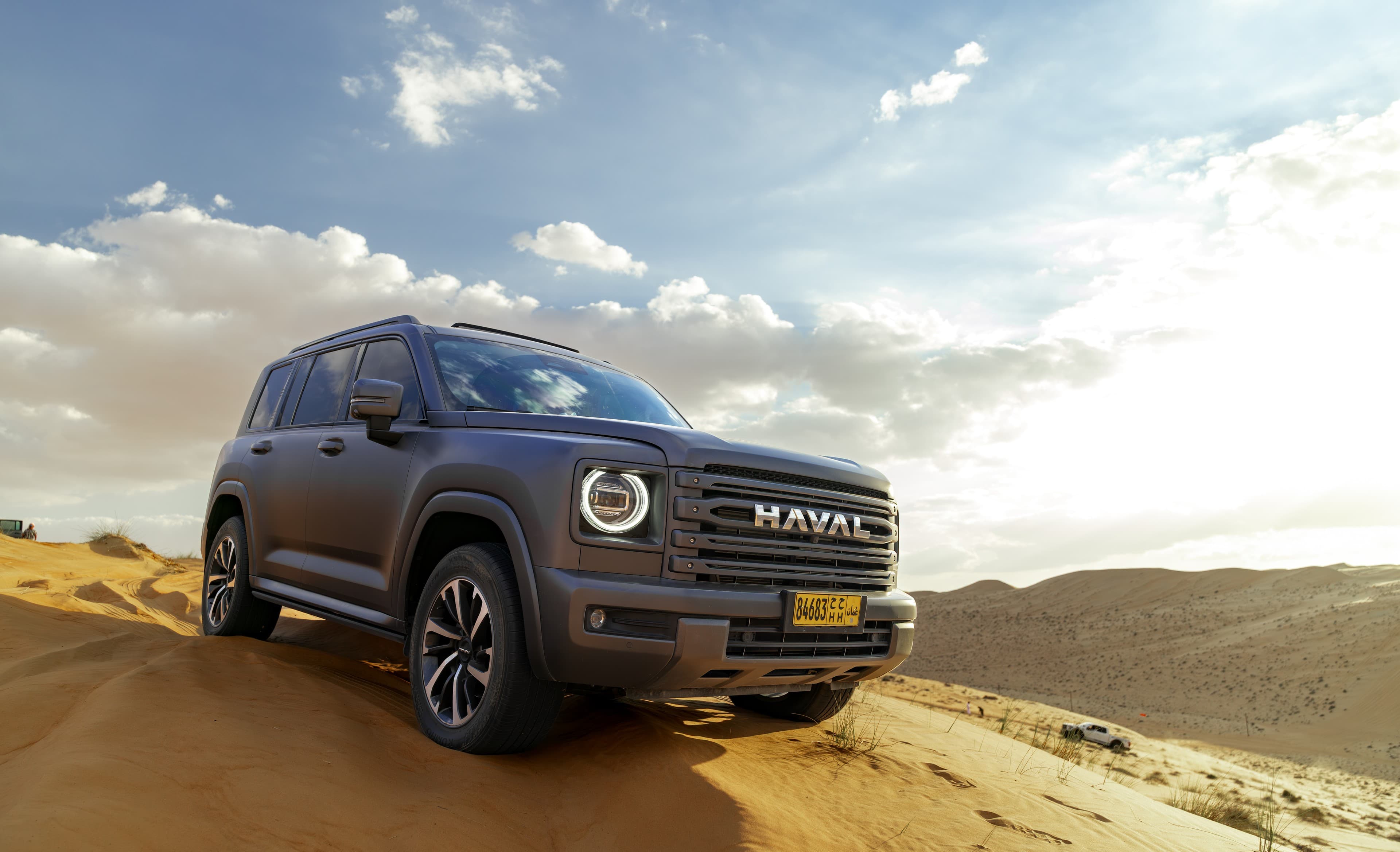 SUV posed on desert dune at sunset