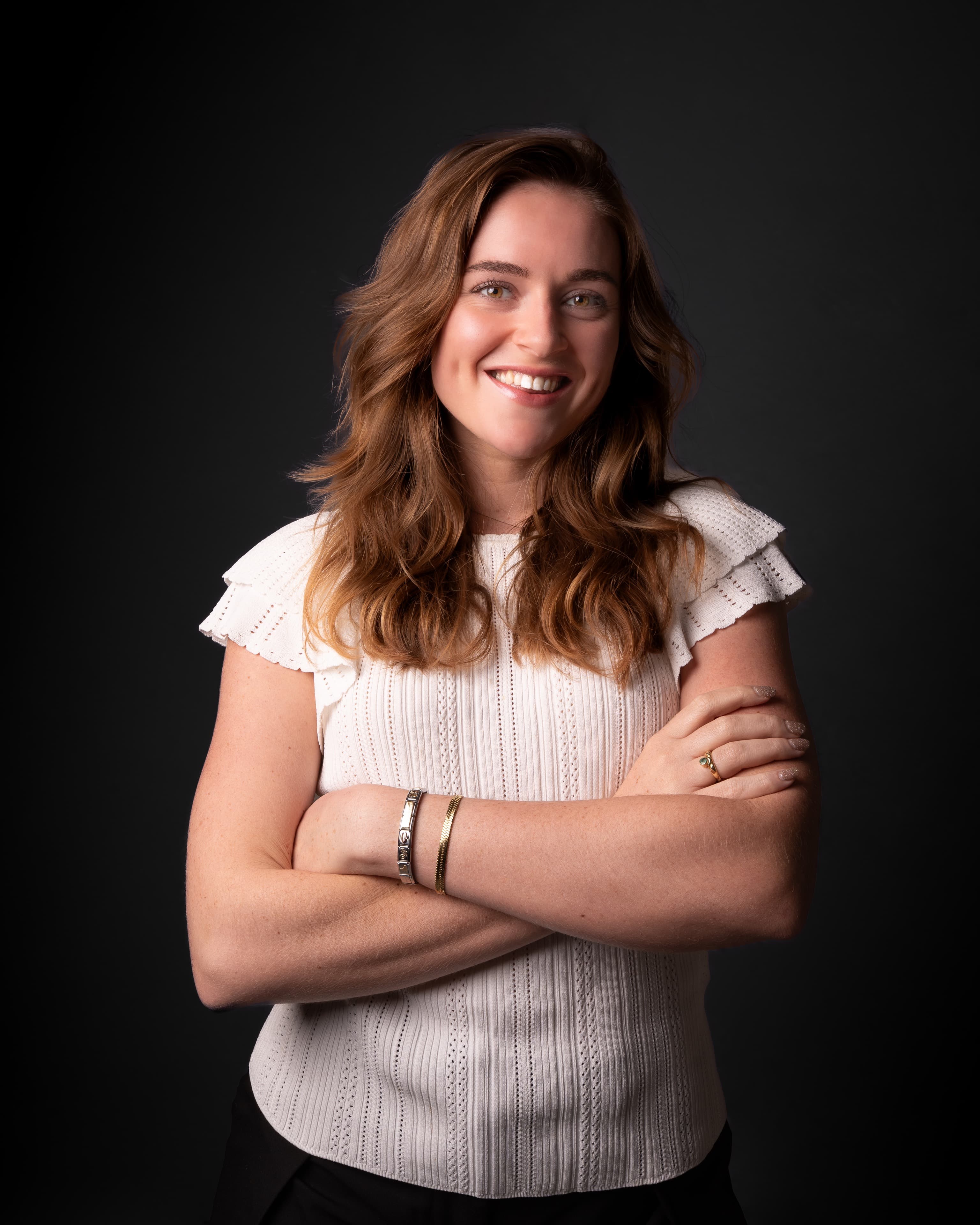 Business portrait of a smiling woman in a white knit top on a dark backdrop